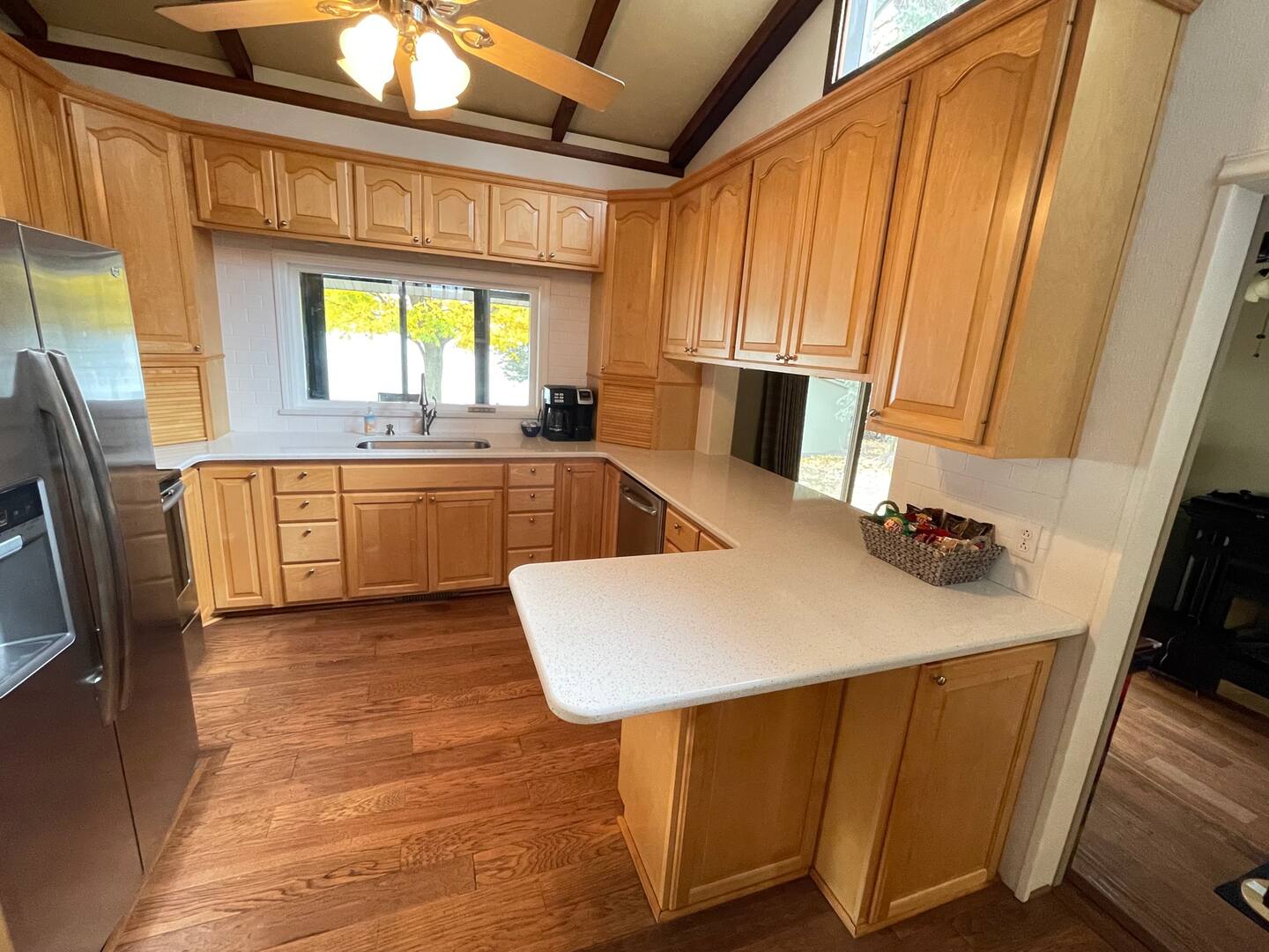 Kitchen with stainless refrigerator, light wooden cabinetry, and ceiling fan.
