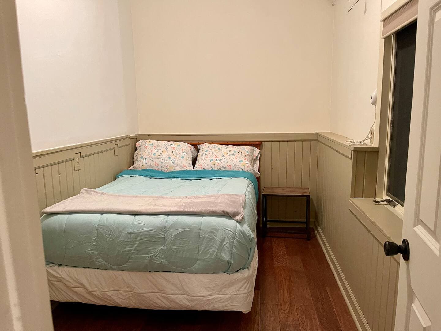 Sweet bedroom with aqua bedding, warm beige wainscoting, and natural wood floors.