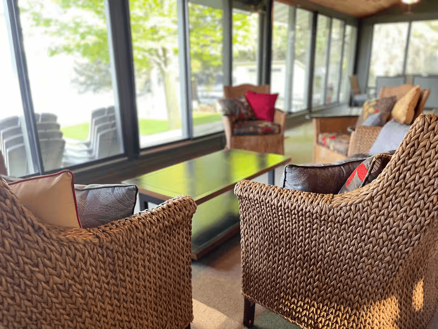 Conversational wicker seating in four-season room with panoramic lake views.