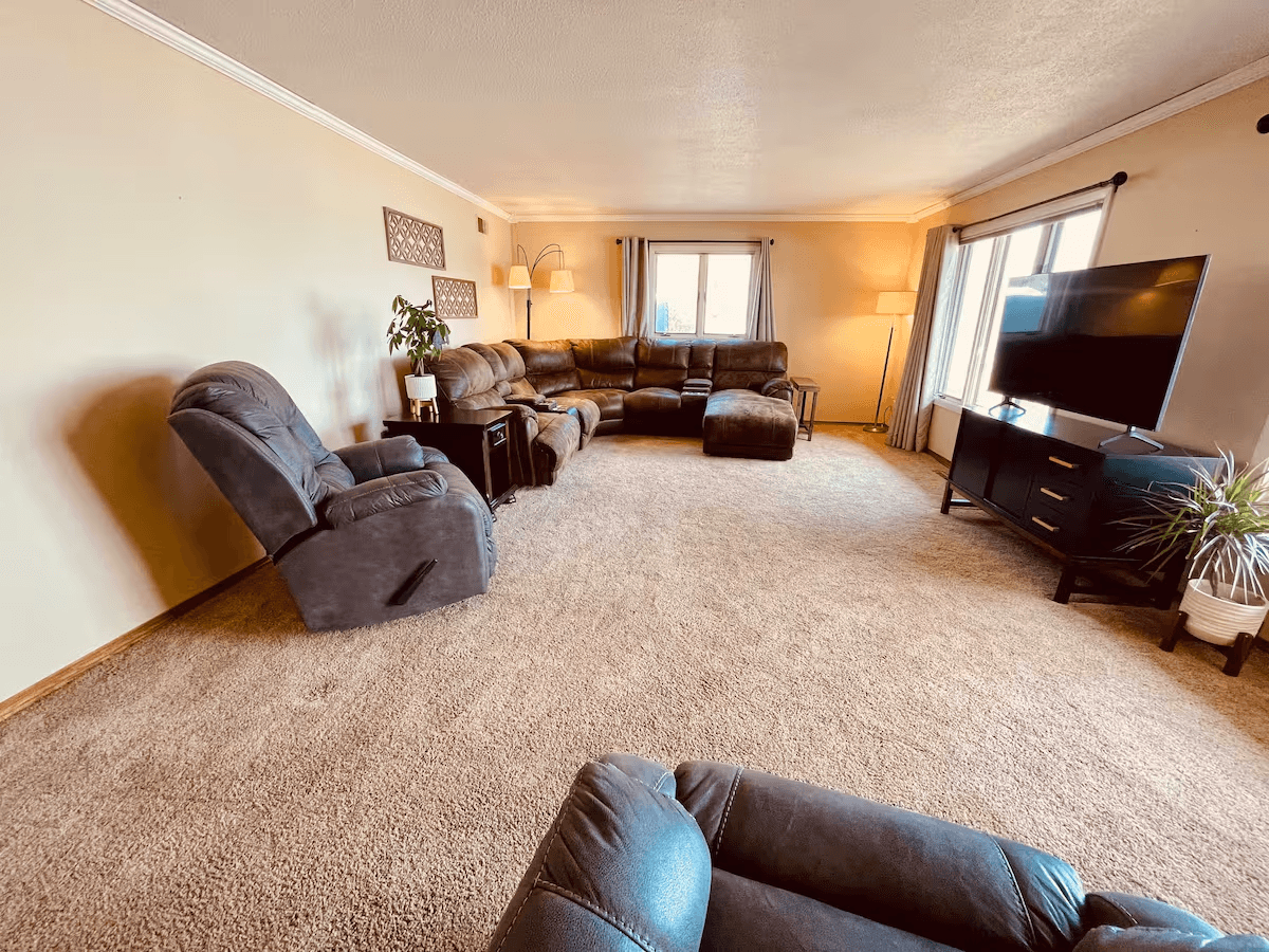 Spacious living room with sectional sofa, recliner, armchair, and flat-screen TV.